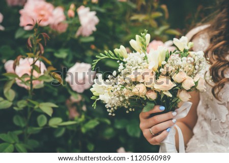 woman is holding wedding bouquet with beige and white flowers