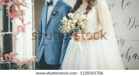 bride and groom walking together with bouquet in hands in dress and blue suit