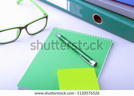 Work place table with folders file on it and modern laptop, pen, glasses and textbook lying near on a white background.