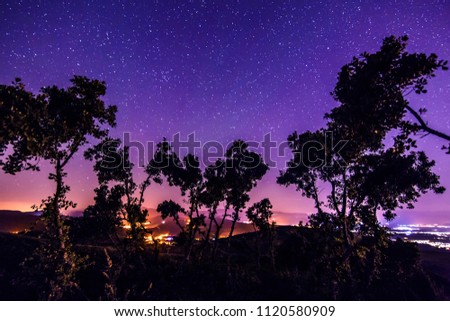 Night landscape with colorful Milky Way and yellow light at mountains.