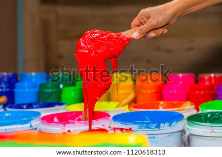 scoop red color of plastisol ink out the barrel in store. several colors of plastisol ink in tee shirt factory main color is blue green yellow orange red and black color 