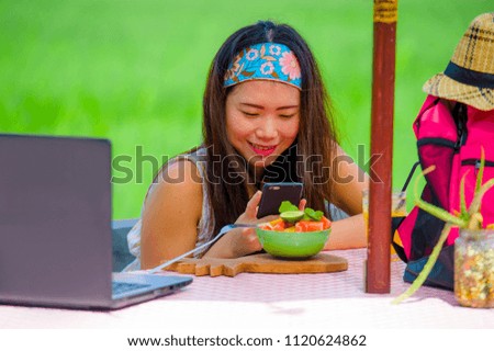 young happy and pretty digital nomad Asian Chinese girl taking picture of fruit salad with mobile phone networking on internet social media in healthy nutrition and travel blogger food review