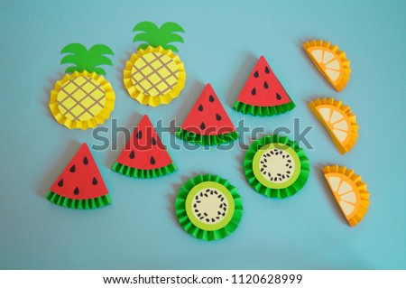 Fruits made from paper on a blue background. Pineapple, orange, lemon, watermelon, kiwi, apple. View from above. Children's creativity. Tropical party of Hawaii.
