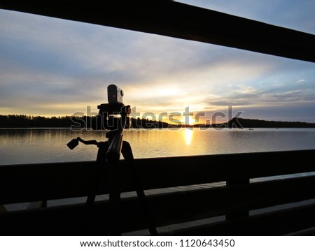 Camera Shooting Sunset Over Beautiful Lake with Cloudy Sky in the background