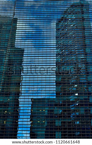 Perspective view of futuristic glass and steel  facade of a modern office tower in downtown Singapore with strong symmetry and geometric patterns as abstract background