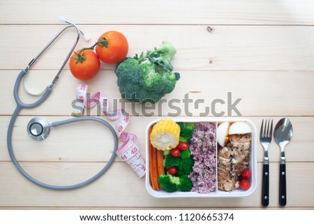Creative flat lay of healthy concept, Stethoscope, measuring tape and chicken breast with vegetables lunch box on wooden background