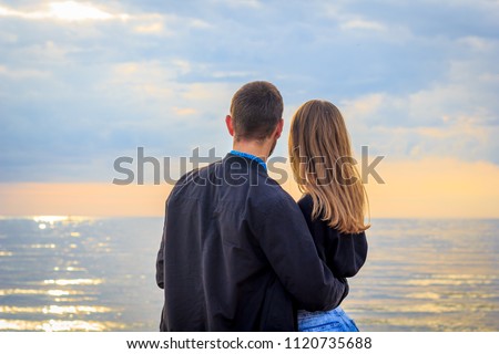 Young couple at sunset by the sea, in love for a walk by the sea at sunset, an unusual sunset with reflection