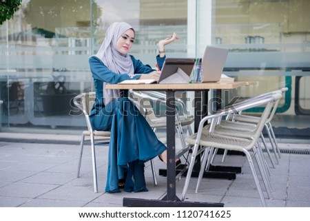 A beautiful muslim businesswoman working with computer in a cafe. Business team meeting brainstorming working concept.