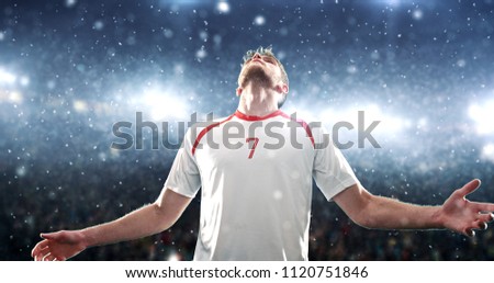 Soccer player celebrates a victory on the professional stadium while it’s snowing. Stadium and crowd are made in 3D.