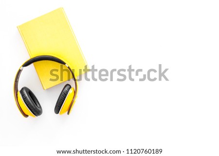Books online concept, audiobooks. Spend leasure time reading and listening music. Headphones near hardback book with empty cover on white background top view copy space