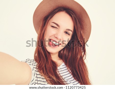 pretty girl in summer hipster clothes take selfie from hands with phone, showing her tongue