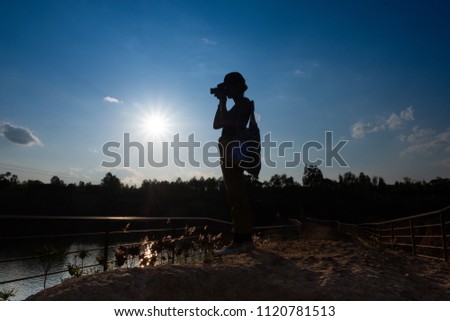 silhouette of asian woman photographer with blue sky background