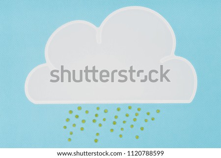 top view of white napkin in shape of cloud with rain of green peas isolated on blue