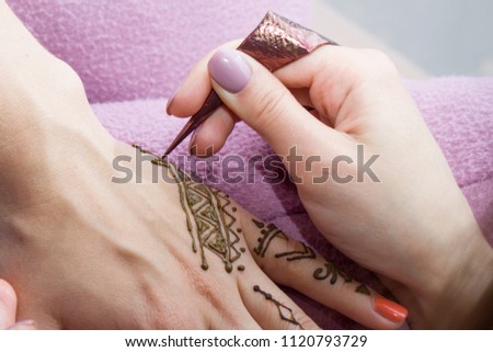 beauty concept - Picture of human hand being decorated with henna Tattoo. mehendi hand
