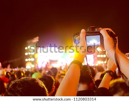 Hands of unidentified record video with digital camera during music festival concert.