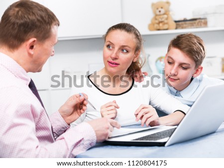 Middle-aged mother and son signing beneficial financial agreement at home