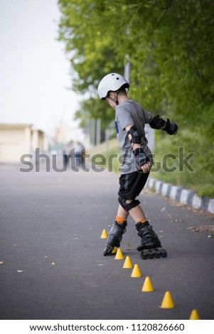 Kid boy roller skating in the park and  doing twists on asphalt 