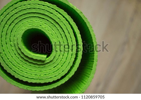 Yoga mat is green on the floor. Healthy lifestyle. Light background, blur back plan.