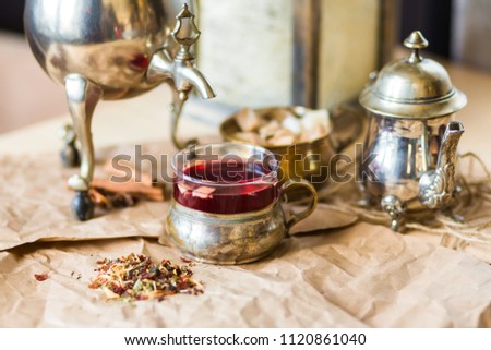 Close-up of fruit tea, karkade. Vintage mug, teapot, samovar, cinnamon, brown sugar. Pleasant tea-party atmosphere. Kraft paper