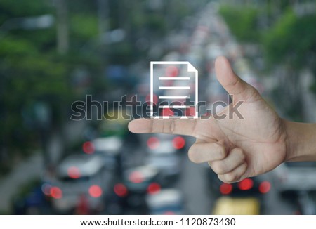Document icon on finger over blur of rush hour with cars and road, Business communication concept