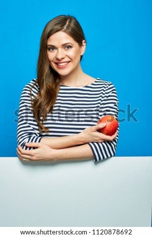 Smiling woman wearing striped dress holding red apple. Portrait with white banner below.