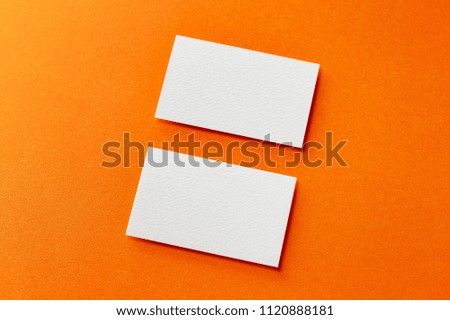 Mockup of two horizontal white blank business cards isolated at orange paper background.