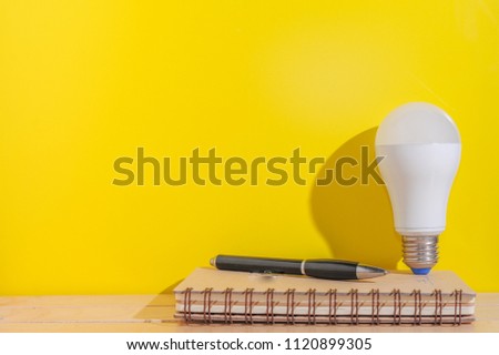 List of idea concept.Idea development concept.Light bulb,Notebook and a pen over yellow background with copy space.