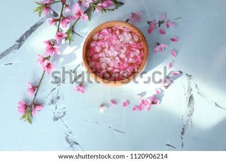 Wooden bowl with water and blooming flowers on table