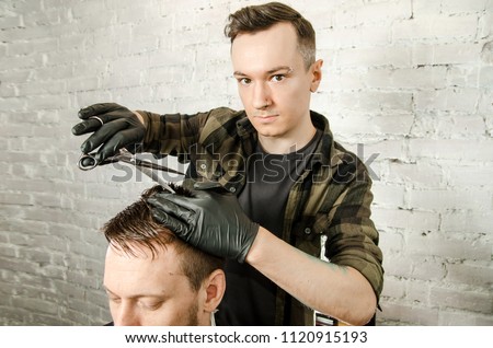 Barber cut hair and comb adult man on a brick wall background. Close up portrait of a guy