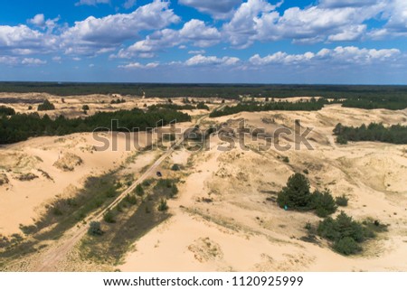 Aerial view on the road in sand dunes. Blue sky with clouds on the background. Picture taken in southern region of Ukraine, national park "Oleshkivski pisk", the largest desert in Europe. June 2018.
