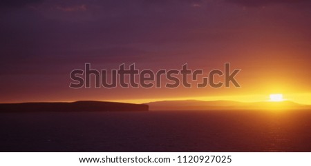 Spectacular midsummer sunset over Orkney from the ferry. The sun sets beteen the thick cloud layer and the well defined cost, providing a perfect sunset light.