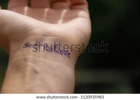 Handwritten motivational phrase on the human hand "Just believe"