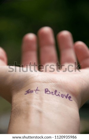 Handwritten motivational phrase on the human hand "Just believe"