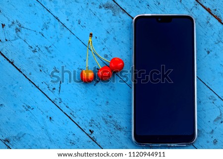 Smartphone and cherry on a wooden table