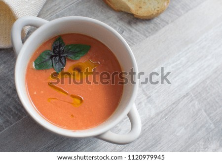 Cold summer Spanish tomato dish. Gazpacho soup with olive oil and basil leaf.
