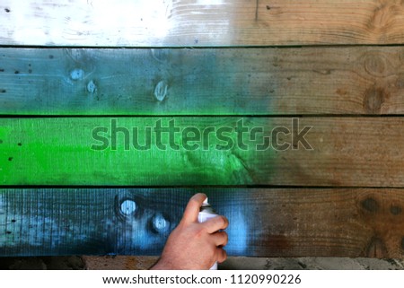 Hand with spray is painting an old wooden surface or pallet.Colorful wood texture Royalty-Free Stock Photo #1120990226