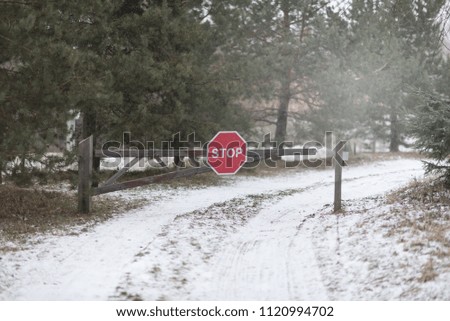 Stop. Red road sign on the barrier. Road closed. Winter with snow. A lot of pines around