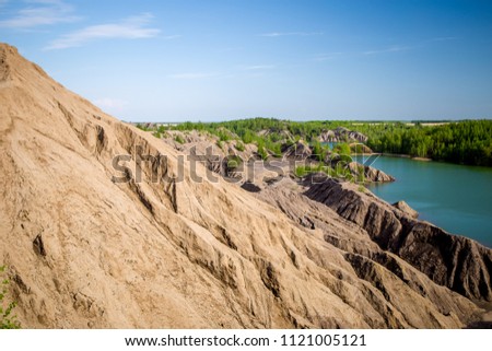 Photo of picturesque hilly area with vegetation and blue lake