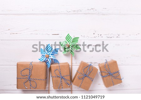 Festive gift boxes with presents  and decorative mindmills on  white  wooden background. Selective focus. Place for text. Flat lay.