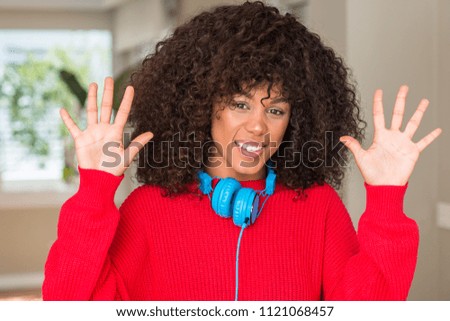 African american woman wearing headphones showing and pointing up with fingers number ten while smiling confident and happy.