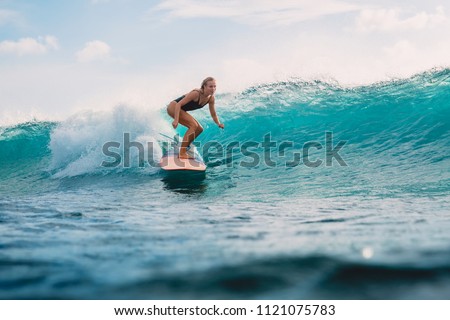 Beautiful surfer girl on surfboard. Woman in ocean during surfing. Surfer and wave Royalty-Free Stock Photo #1121075783