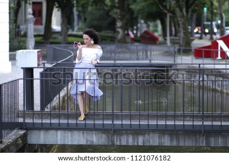 women  brunette in the town ,walking ,standing and posing near the river,wearing juppe  blue and blouse white.