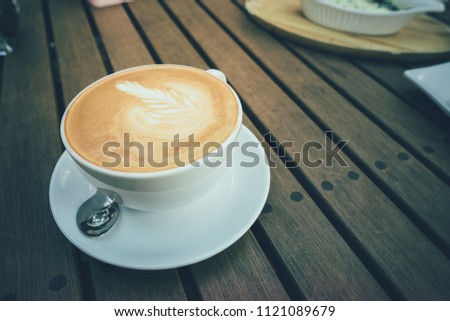 Coffee latte on the wooden table at coffee shop., vintage color style.