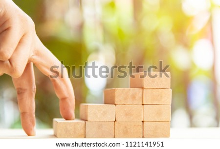 Concepts of building a staircase and step up of wooden pegs for another entrepreneur to climb up the ladder of success.Two finger walking motion step on block wood for close project. Royalty-Free Stock Photo #1121141951