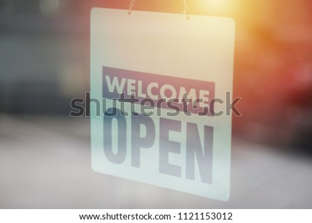 Open and welcome sign broad through the glass of window to let customers know