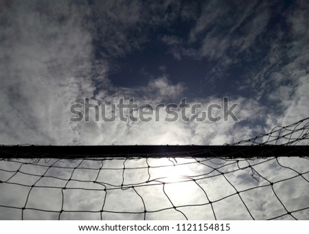 Silhouette crossbar of soccer goal and net with cloud and blue sky background.