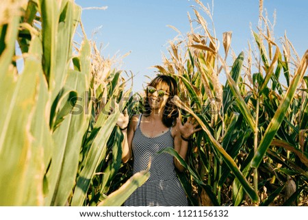 Young pretty woman standing in a green and yellow corn field. She is very happy, relaxed and carefree. Feel concept. Lifestyle.