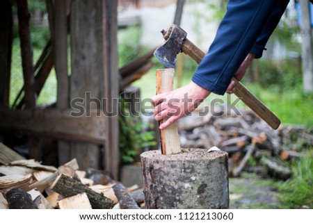 Man hands cutting some piece of wood by axe