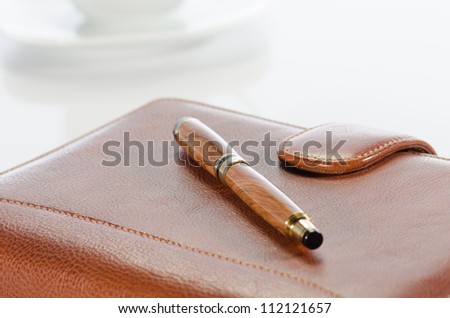  Pen and  leather notebook against a  white background