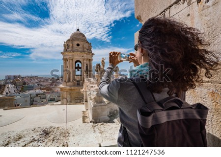 Young woman taking picture of the roofs of Cadiz, Spain.